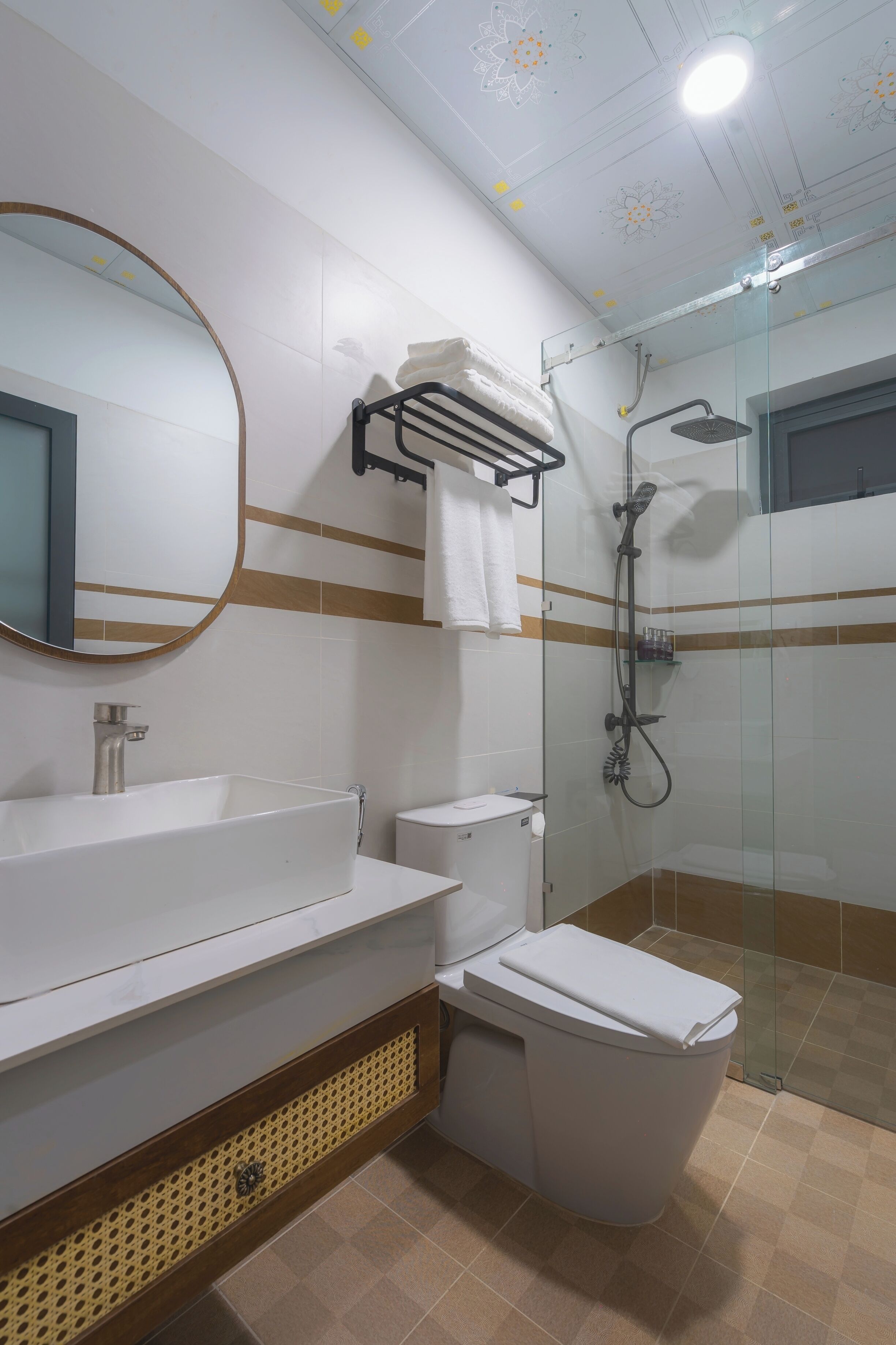 A modern bathroom with a large mirror, a white sink, a toilet, and a glass-enclosed shower area.