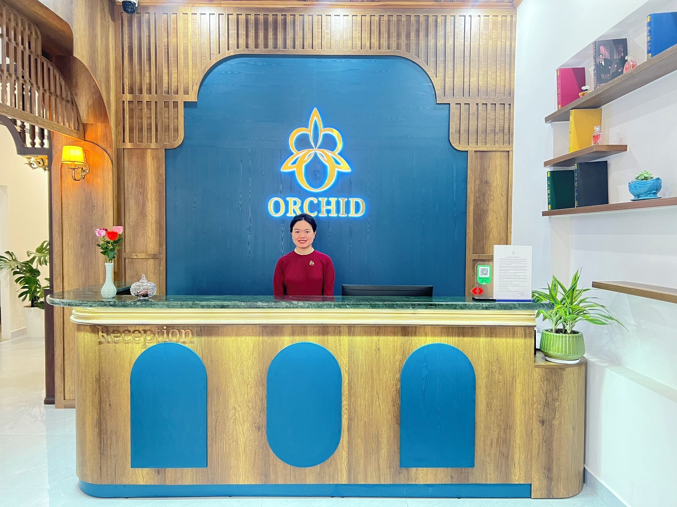 A reception desk with a blue and wooden design, featuring the Orchid logo.