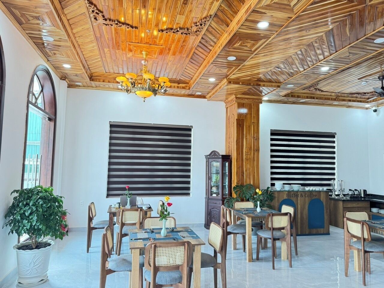 A dining area with wooden tables and chairs, a buffet counter, and a chandelier.