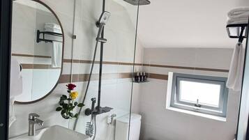 A bathroom with a shower, toilet, sink, and a window.