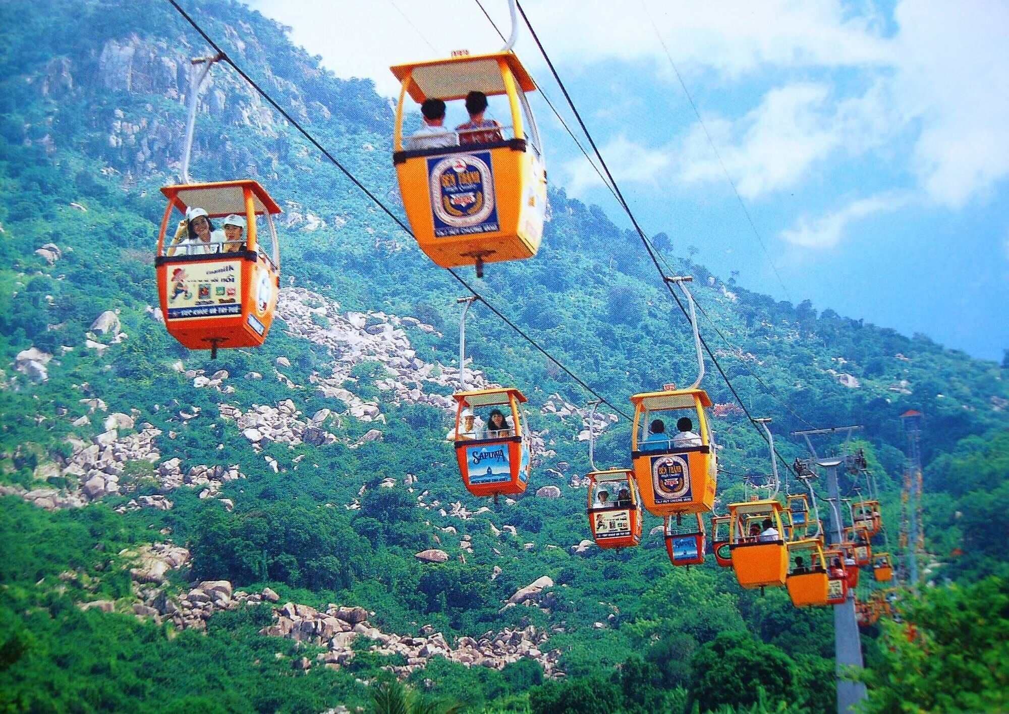 A cable car system with passengers, set against a mountainous backdrop.