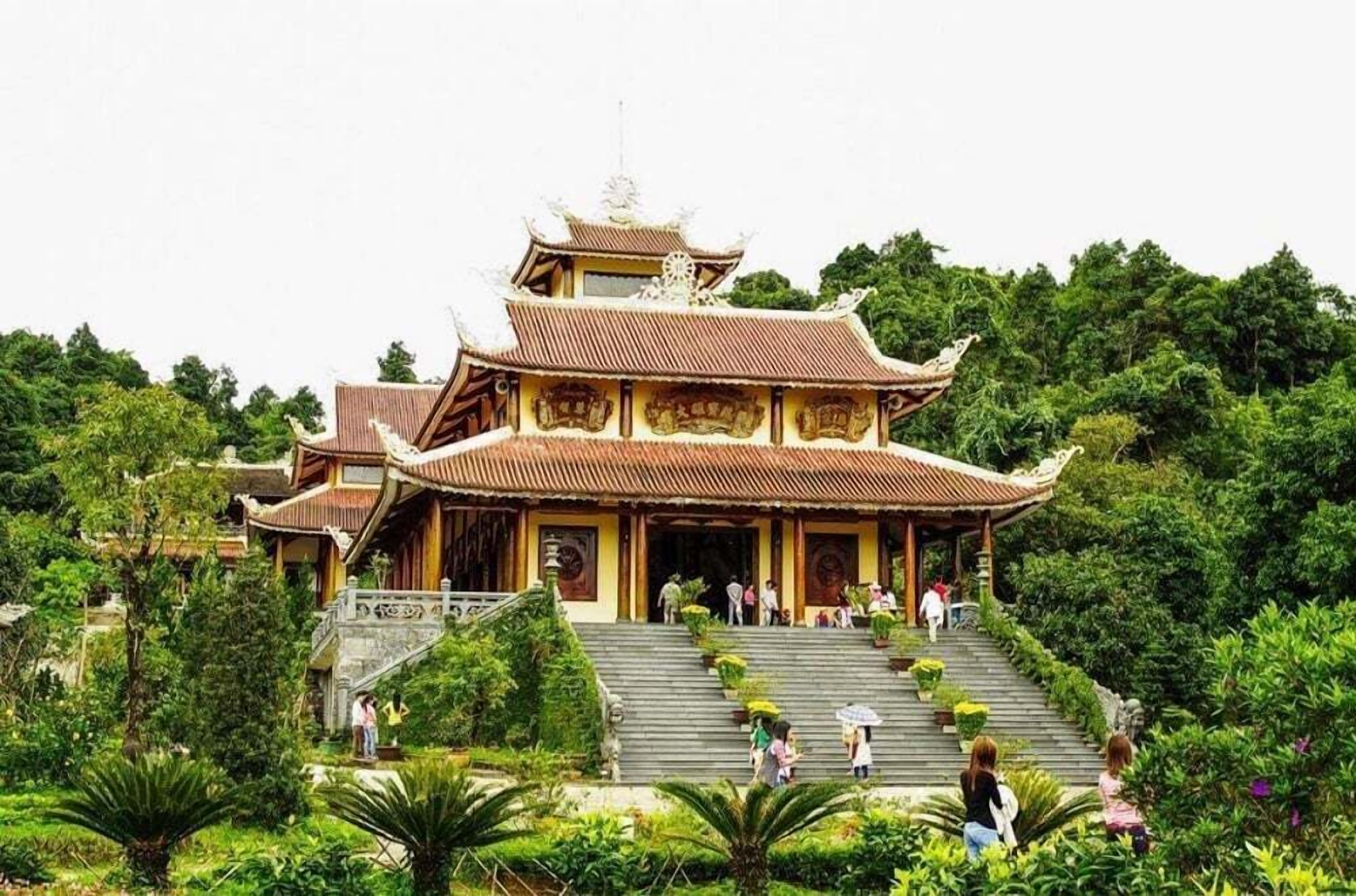 A traditional multi-tiered temple with a staircase leading to the entrance, surrounded by lush greenery.