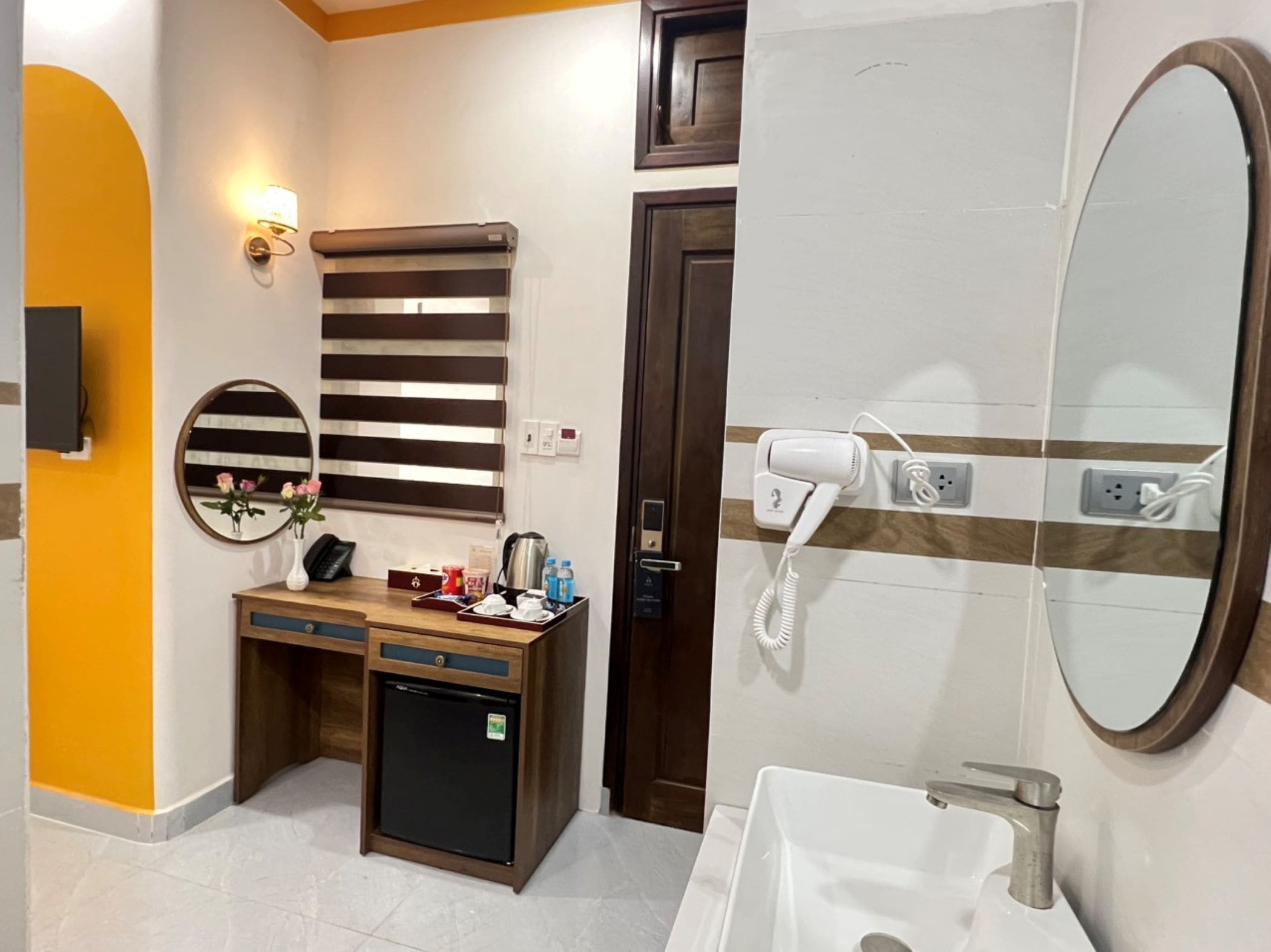 A bathroom with a sink, mirror, towel rack, and a hairdryer on the wall.