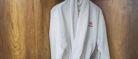 A white robe hanging on a wooden door with a metal handle.