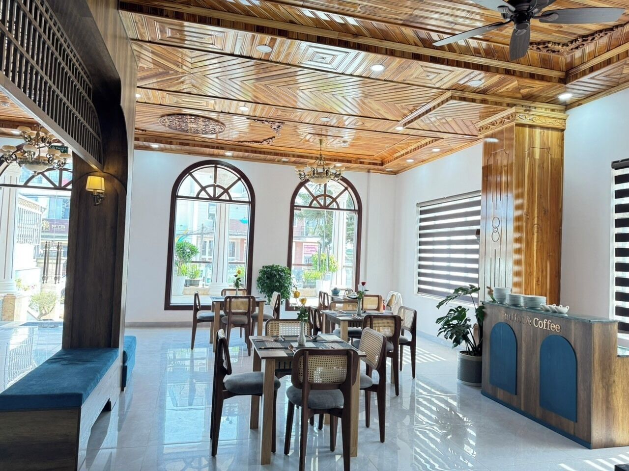 A restaurant with a wooden ceiling, large windows, and a reception desk.