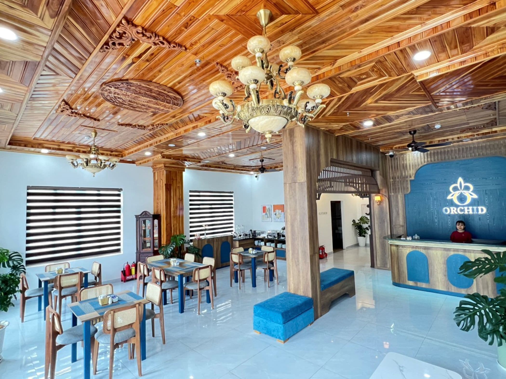 Vestíbulo de hotel con techo de madera, una recepción y zonas de estar.