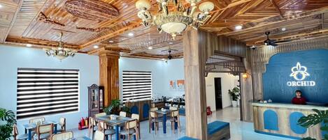 A hotel lobby with wooden ceiling, a reception desk, and seating areas.