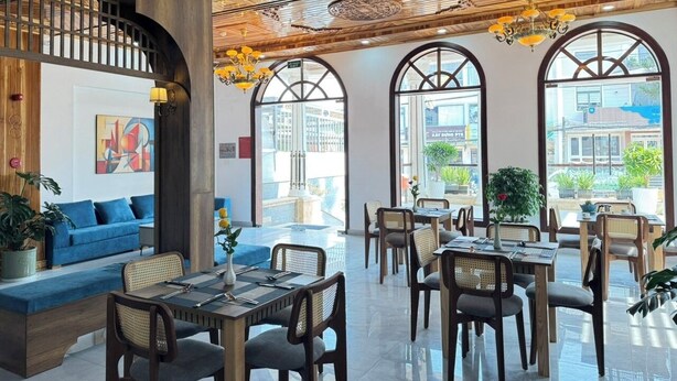 A modern hotel lobby with a wooden ceiling, large arched windows, and a seating area with tables and chairs. - ORCHID Hotel (Lam Vien - Da Lat)