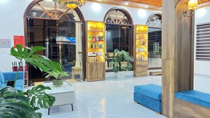 A lobby with a chandelier, wooden columns, and a seating area. - ORCHID Hotel (Lam Vien - Da Lat)
