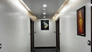 A hallway with a polished black marble floor, white walls, and two doors. - Hotel kailash inn (Garudeshwar)