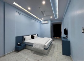 A modern bedroom with a bed, nightstand, air conditioning unit, ceiling fan, and a TV on a stand.