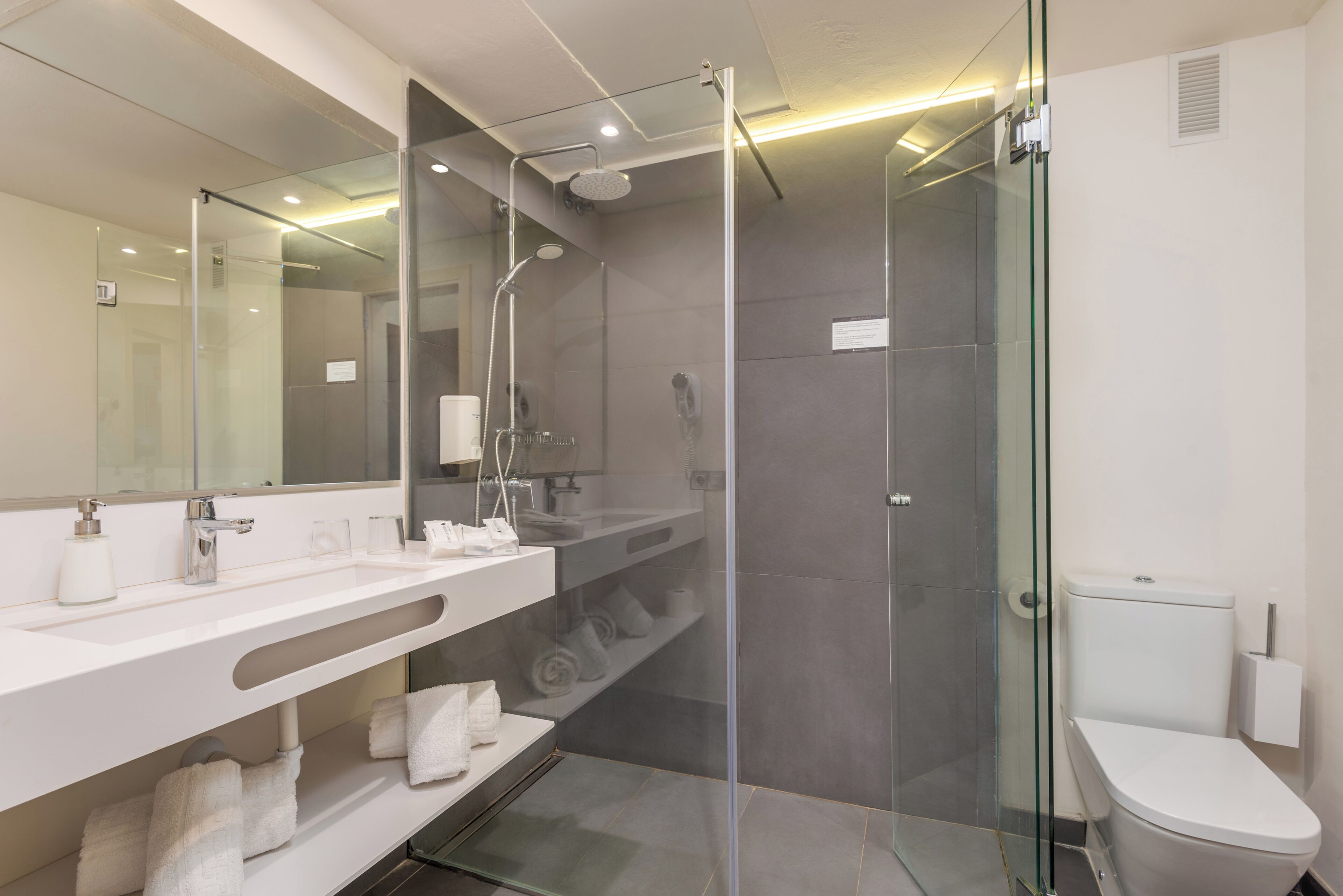 Un baño moderno con ducha acristalada, lavabo blanco y retrete.