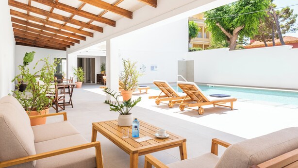 Un espace aménagé au bord de la piscine, avec des meubles en bois, des plantes en pot et une vue sur la piscine et la végétation environnante.