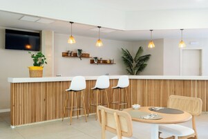 A modern kitchen with a wooden island, bar stools, and pendant lighting.