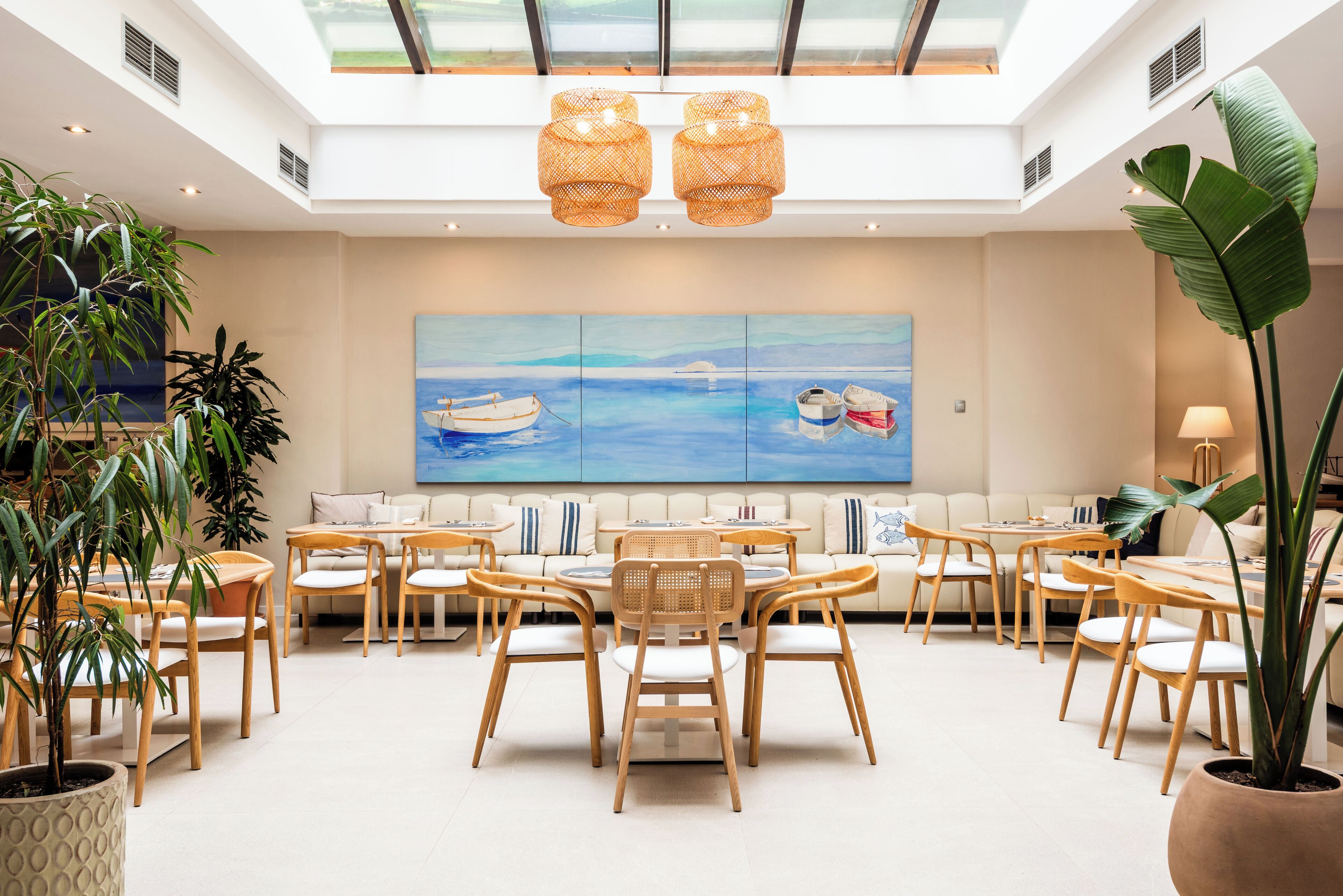 A spacious room with a high ceiling, a large painting of a seascape, and a dining area with wooden furniture.