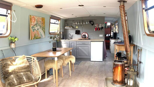 A compact kitchen with a dining area, a stove, and a hanging pot rack. - 5 Star Stunning Houseboat, no Experience Required! Enjoy the Most Romantic Trip! (Monasterevin)