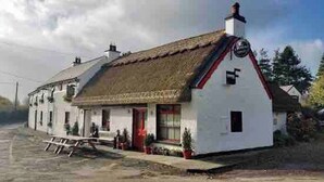 A white building with a thatched roof, a small porch, and a red door. - 5 Star Stunning Houseboat, no Experience Required! Enjoy the Most Romantic Trip! (Monasterevin)