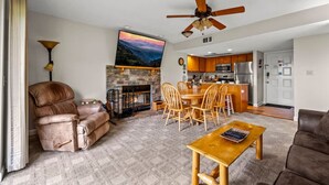 A living room with a fireplace, a dining area, and a kitchen in the background. - Full Kitchen Hot Tub Indoor Pool Sleeps 6 (Gatlinburg)