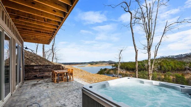 A hot tub on a patio with a view of a lake and trees. - NEW Lake View Indoor Pool Sleeps 14 Hot Tub (Sevierville)