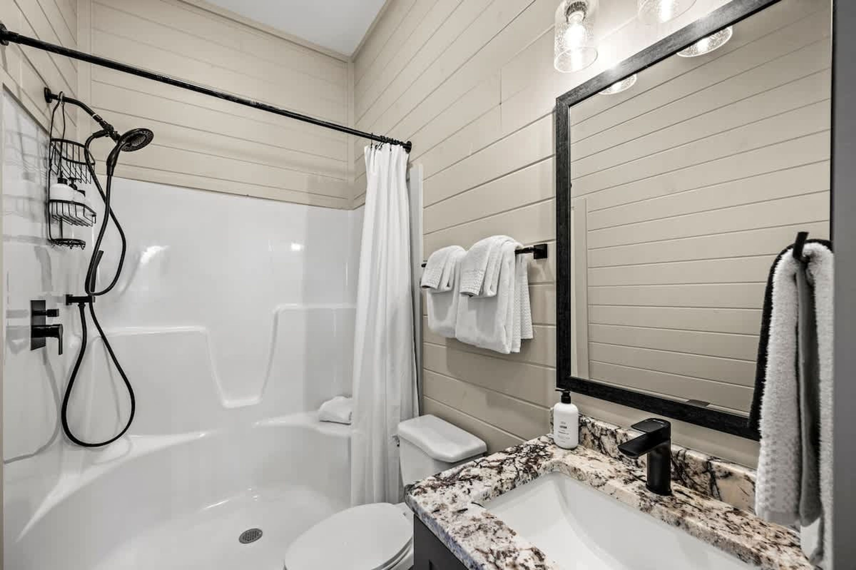 A modern bathroom with a walk-in shower, toilet, and sink.