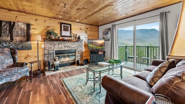 Ein gemütliches Wohnzimmer mit Kamin, Holzboden und einem Balkon mit Bergblick.