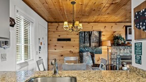Eine Küche mit Granitarbeitsplatten, einer Edelstahlspüle, Holzboden und einem Chandelier.