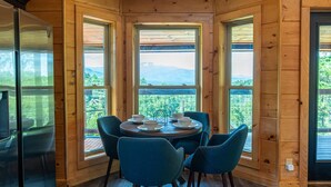 A wooden cabin interior with a dining table set for four, surrounded by four chairs, and a refrigerator to the left. - Mountain Views Sauna Hot Tub Fire Pit (Gatlinburg)