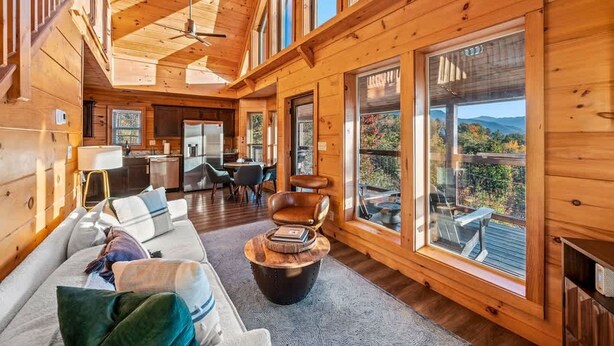 A spacious wooden cabin interior with a dining area, kitchen, and large windows offering scenic views. - Mountain Views Sauna Hot Tub Fire Pit (Gatlinburg)