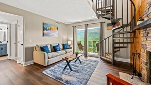 A living room with a sofa, coffee table, and a spiral staircase.
