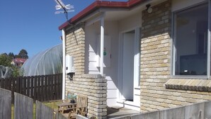 Una casa con techo rojo, fachada de ladrillo y un ventanal grande.