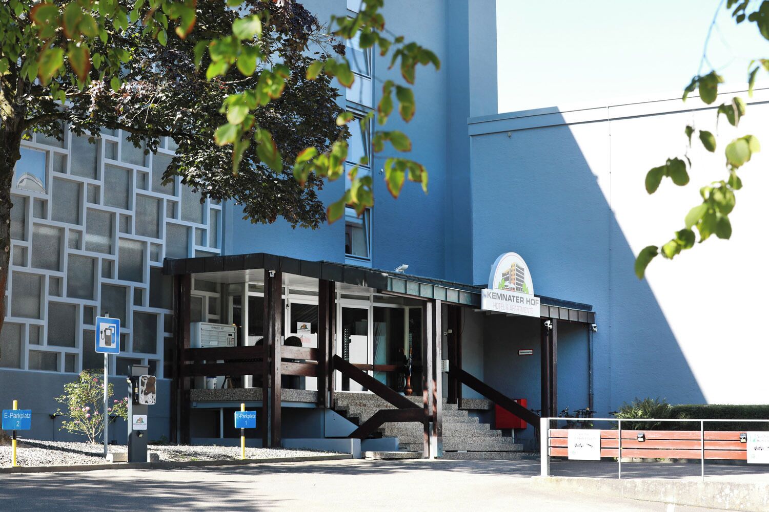 A hotel entrance with a blue facade, a staircase leading to the entrance, and a sign indicating the hotel name.