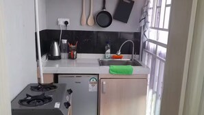 Une cuisine de taille réduite, équipée d’une cuisinière à gaz, d’un petit réfrigérateur et d’un évier.