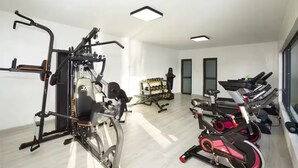 Une salle de sport moderne équipée de divers appareils d’exercice, notamment un vélo d’appartement, un appareil elliptique et des tapis de course.