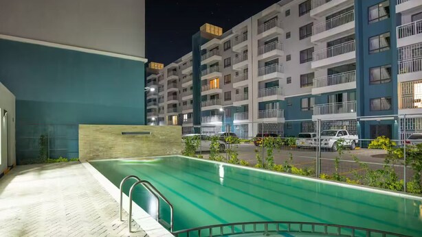Un espace piscine offrant une vue sur des immeubles résidentiels à plusieurs étages, de nuit.