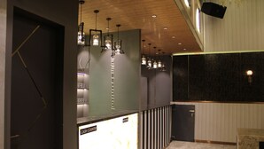 A modern reception area with a cash counter, pendant lighting, and a marble floor.