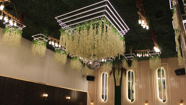 A modern interior with hanging floral arrangements, geometric light fixtures, and mirrored wall panels.