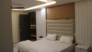 A modern bedroom with a large bed, built-in headboard, bedside tables, and a ceiling fan.