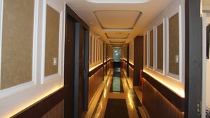 A hotel hallway with a central lighted path, wooden paneling, and a modern ceiling design.