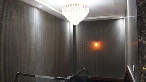 A modern interior with a metallic wall, a glass railing, and a chandelier.