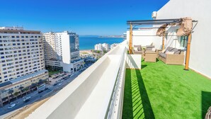 Ein Balkon mit Meerblick, einer Grünfläche und Stadtgebäuden.