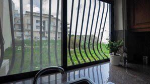A kitchen with a large window, a potted plant, and a view of a residential building.