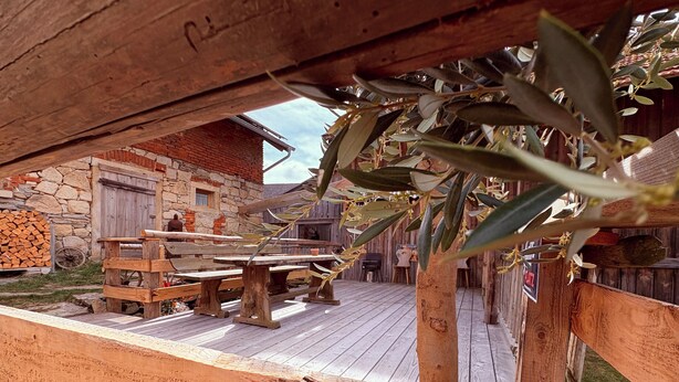 An outdoor wooden deck with rustic benches and a stone building in the background.
