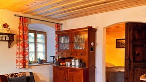 A cozy room with a wooden ceiling, a sofa, a cabinet, and a rug.