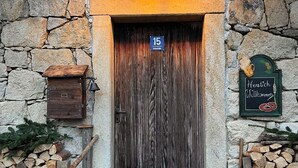 A rustic wooden door with a number sign, a welcome sign, and stacked firewood on either side.