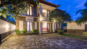 A two-story house with a paved driveway, stone walls, and a balcony. - Villa Sabasanti (Blahbatuh)