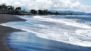 A beach with waves, a clear sky, and a distant mountain range. - Villa Sabasanti (Blahbatuh)
