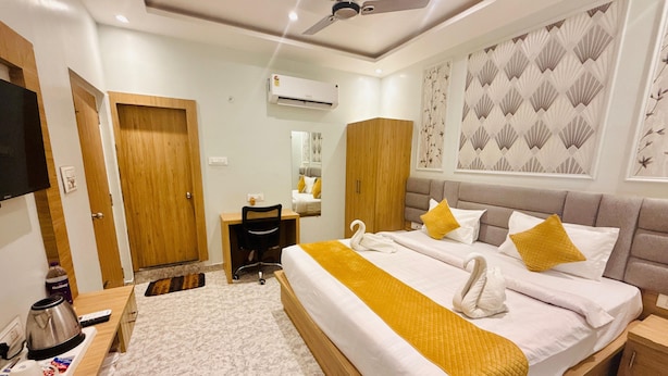 A hotel room with a large bed, a desk, a chair, a wardrobe, an air conditioner, and a television. - HOTEL RUDRA RESIDENCY (Patna)