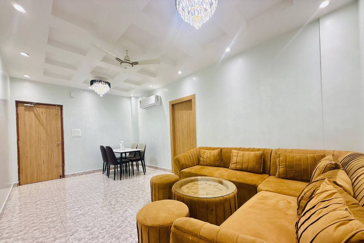 A spacious living area with a large sofa, a round coffee table, and a dining table with chairs.