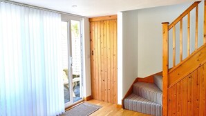 Un couloir avec un escalier en bois, une porte-fenêtre coulissante et un banc.