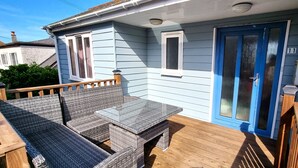 A house with a blue door, a small porch with wicker furniture, and a number '11' on the wall.
